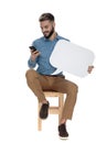 Seated fashion man reads a sms on his phone