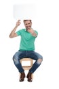 Seated happy man holds a blank talk billboard up