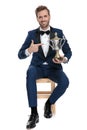 Seated happy man is pointing his finger to trophy cup