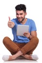 Seated happy man reading good news on his tablet Royalty Free Stock Photo