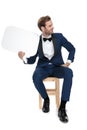 Seated luxury man looks away with chat bubble in hand Royalty Free Stock Photo