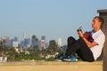 Seated man playing acoustic guitar with LA skyline Royalty Free Stock Photo