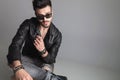 Seated man wearing sunglasses and leather jacket looks to side Royalty Free Stock Photo