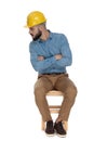 Seated unshaved man looking close careful with arms folded Royalty Free Stock Photo