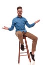 Seated young casual man making a welcoming gesture