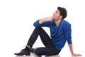 Seated young man in blue jeans and shirt looking up