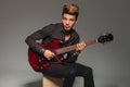 Seated young man playing an electric guitar