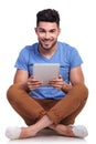 Seated young man with tablet pad smiling Royalty Free Stock Photo