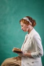 Seated young woman, dressed in retro style, reading a book Royalty Free Stock Photo