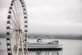 Seattle ferry passing by Great Wheel on foggy day