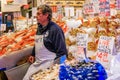 Seattle, United States - November Fishmonger at a stall with fresh seafood like crab, shrimp and mussels for sale at