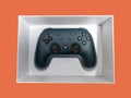 Closeup of a Google Stadia gaming controller inside a white box against a colorful Royalty Free Stock Photo