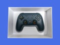 Closeup of a Google Stadia gaming controller inside a white box against a colorful Royalty Free Stock Photo