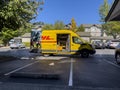 Seattle, WA USA - circa October 2022: Wide angle view of a DHL delivery van making a stop in a large apartment complex on a bright