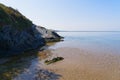 Seaweed on wet rippled sand in the shadow of slate cliffs Royalty Free Stock Photo