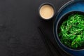 Seaweed salad with sesame seeds in a black bowl, peanut sauce and chopsticks on a black background Royalty Free Stock Photo