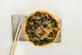 Seaweed salad with sesame seeds on round bamboo plate on stand made of natural gray stone . trending image of traditional Asian