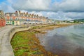 The seaweed strewn Swanage beach with a glassy lapping colourful sea