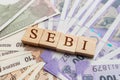 SEBI in wooden block letters on Indian Currency Royalty Free Stock Photo