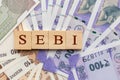 SEBI in wooden block letters on Indian Currency Royalty Free Stock Photo