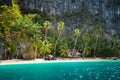 Secluded remote beach with hut under palm trees on Pinagbuyutan Island. Amazing lime stone rocks, sand beach, turquoise blue