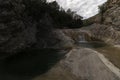 A secluded waterfall flows into a serene pond, surrounded by rocky terrain and lush greenery, evoking a sense of tranquility Royalty Free Stock Photo