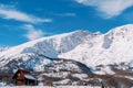 Secluded wooden cottage in a small snowy village at the foot of the mountains