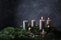 Second advent with two burning candles on fir branches with Christmas decoration against a dark grey background, copy space