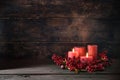 Second Advent with two lit red candles in a wreath from berries with Christmas decoration against a dark rustic wooden background Royalty Free Stock Photo
