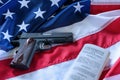 The second amendment and gun control in the US, concept. A handgun and the american constitution on the USA flag. Royalty Free Stock Photo