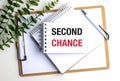 Second chance message on white notepad with clipboard, pen and green leaves on white background Royalty Free Stock Photo