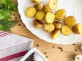 second courses, baked potatoes cooked in a rustic way, in a white plate on a wooden table with herbs, mushrooms and spices, view f