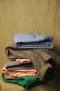 second-hand clothes are stacked on top of each other blue jeans knitted sweater and colored green and pink pants Royalty Free Stock Photo