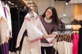 Second hand. Young Caucasian woman chooses sweater in store. In background there are d hangers with clothes. Concept of Royalty Free Stock Photo