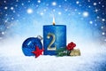 Second sunday of advent blue candle with golden metal number red decoration one on wooden planks in snow front of silver panorama Royalty Free Stock Photo