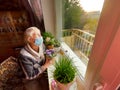 The Covid-19, health, safety and pandemic concept - senior old lonely woman sitting near the window Royalty Free Stock Photo