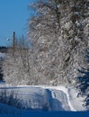 Secondary countryside alpine road in remote mountain village, snow drifts and wood fence on wayside