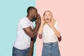 The young couple whispering a secret behind her hand over studio background Royalty Free Stock Photo