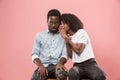 The young woman whispering a secret behind her hand to afro man Royalty Free Stock Photo