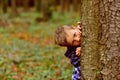 A secret little place. Little boy hide behind tree. Small boy play peekaboo in woods. This is my secret place