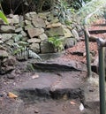 Secret Path in Garden With Steps and Wooden Rail Branch and Stonework Royalty Free Stock Photo