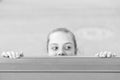 Secret place for hiding. Cute small child hiding under the table. Little girl hiding and peeping out with curiosity Royalty Free Stock Photo