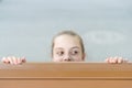 Secret place for hiding. Cute small child hiding under the table. Little girl hiding and peeping out with curiosity Royalty Free Stock Photo