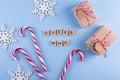 Secret Santa christmas game. Gift exchange. Wrapped gift boxes with notes candy cane on blue pastel background top view copyspace. Royalty Free Stock Photo