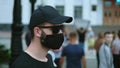 Secret service agent in black glasses, cap and mask on rioting protesters rally.
