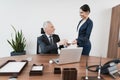 The secretary brought her boss a cup of coffee. He sits at his desk in front of an open laptop