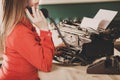 Secretary at old typewriter with telephone. Young woman using ty Royalty Free Stock Photo