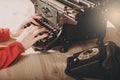 Secretary at old typewriter with telephone. Young woman using ty Royalty Free Stock Photo