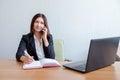 Secretary talking on mobile phone and writing notes while sitting at her desk. Royalty Free Stock Photo