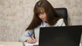 Secretary writes pen in notebook. girl sitting in chair in office at computer and takes notes in notebook. young female Royalty Free Stock Photo